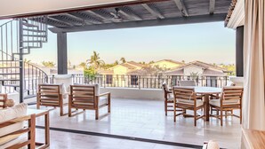A spacious balcony with wooden furniture, a spiral staircase, and a view of houses in the background. - Bohari (San José del Cabo)