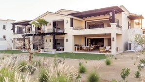 A two-story house with a covered patio, outdoor seating area, and a landscaped garden. - Bohari (San José del Cabo)