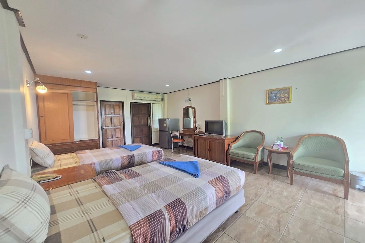 Une chambre d’hôtel avec deux lits, un bureau, une télévision et deux chaises.
