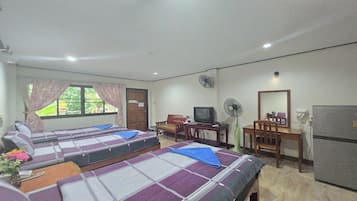 Quarto com duas camas, uma escrivaninha, televisão e frigorífico.