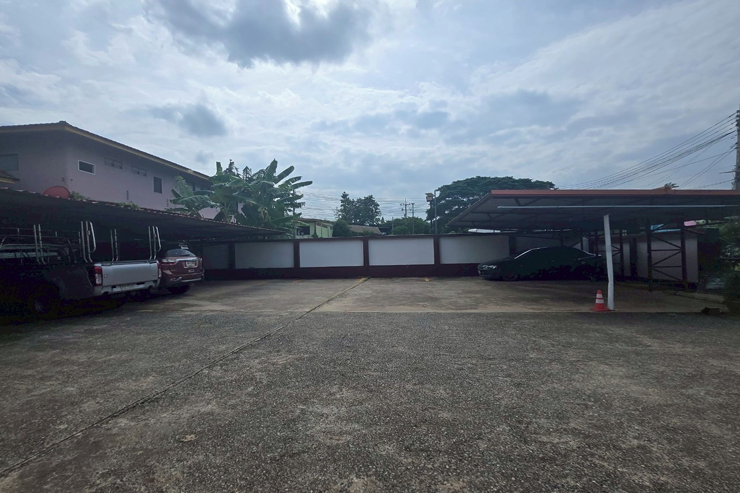 Uma área de estacionamento com superfície de concreto, uma garagem coberta e um edifício com telhado plano.