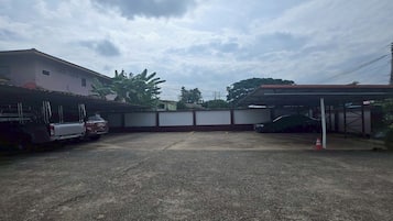 Uma área de estacionamento com superfície de concreto, uma garagem coberta e um edifício com telhado plano.