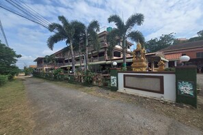 A multi-story building with a balcony, surrounded by a fence and palm trees. - Phaiboon Hotel & Resort By Zuzu (Pak Chong)