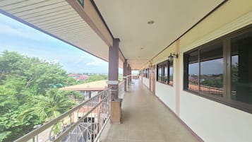 Um corredor coberto com vista para vegetação e edifícios.
