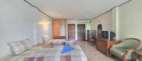 A hotel room with two beds, a wooden cabinet, a television, and a green armchair.