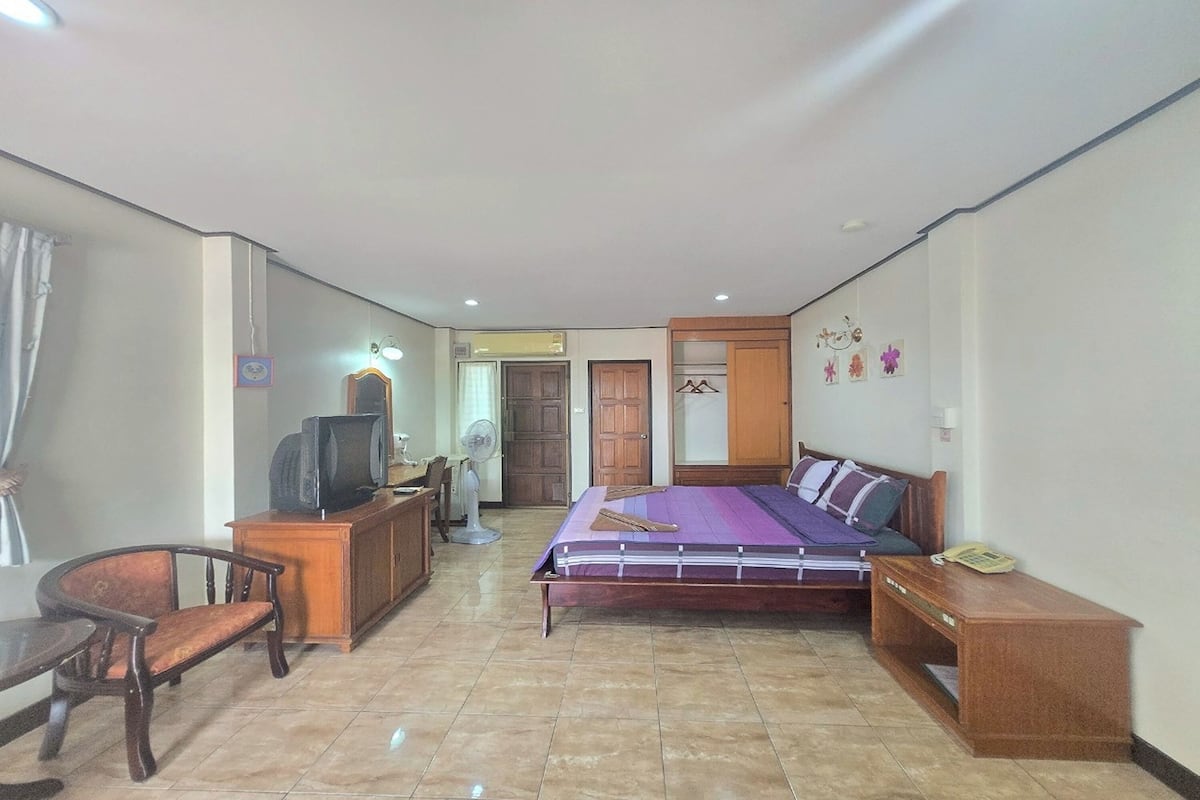 Une chambre à coucher comprenant un lit, un bureau, une chaise, une télévision et une armoire.