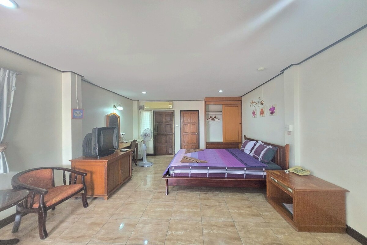 Une chambre à coucher comprenant un lit, un bureau, une chaise, une télévision et une armoire.