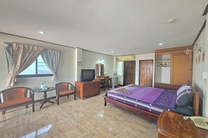 Een hotelkamer met een bed, een bureau, een stoel, een televisie en een kledingkast.