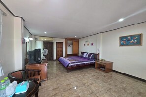 A bedroom with a bed, a desk, a chair, a fan, and a small table. - Phaiboon Hotel & Resort By Zuzu (Pak Chong)