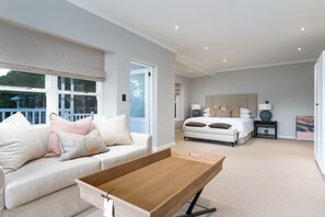 A modern bedroom with a large bed, a bedside table, and a window with a view of the outside.