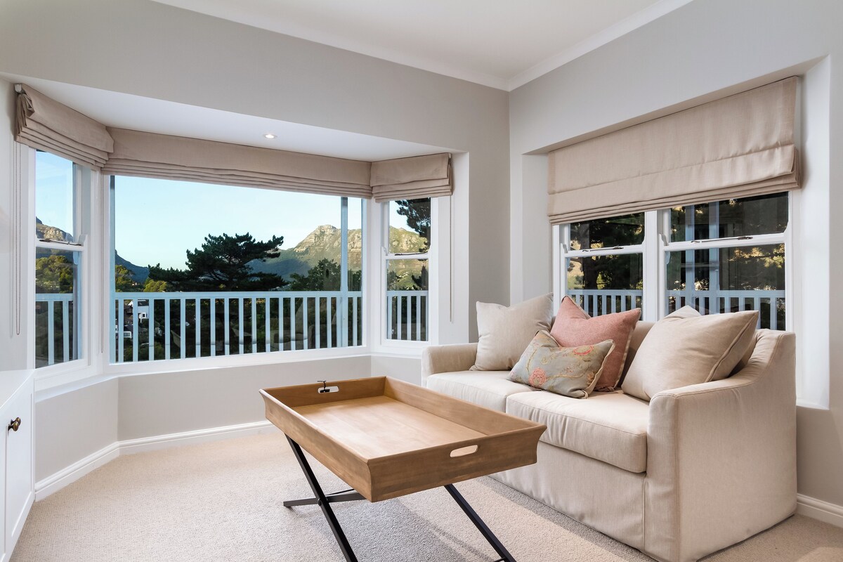 A room with a beige sofa, a wooden tray table, and large windows with white railings.
