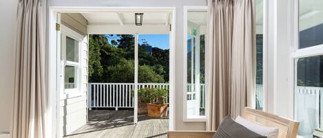 A balcony with a wooden floor, white railings, and a potted plant.
