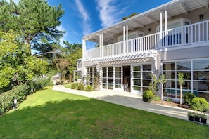 Une maison à deux étages dotée d’un balcon, de grandes fenêtres et d’une pelouse bien entretenue.