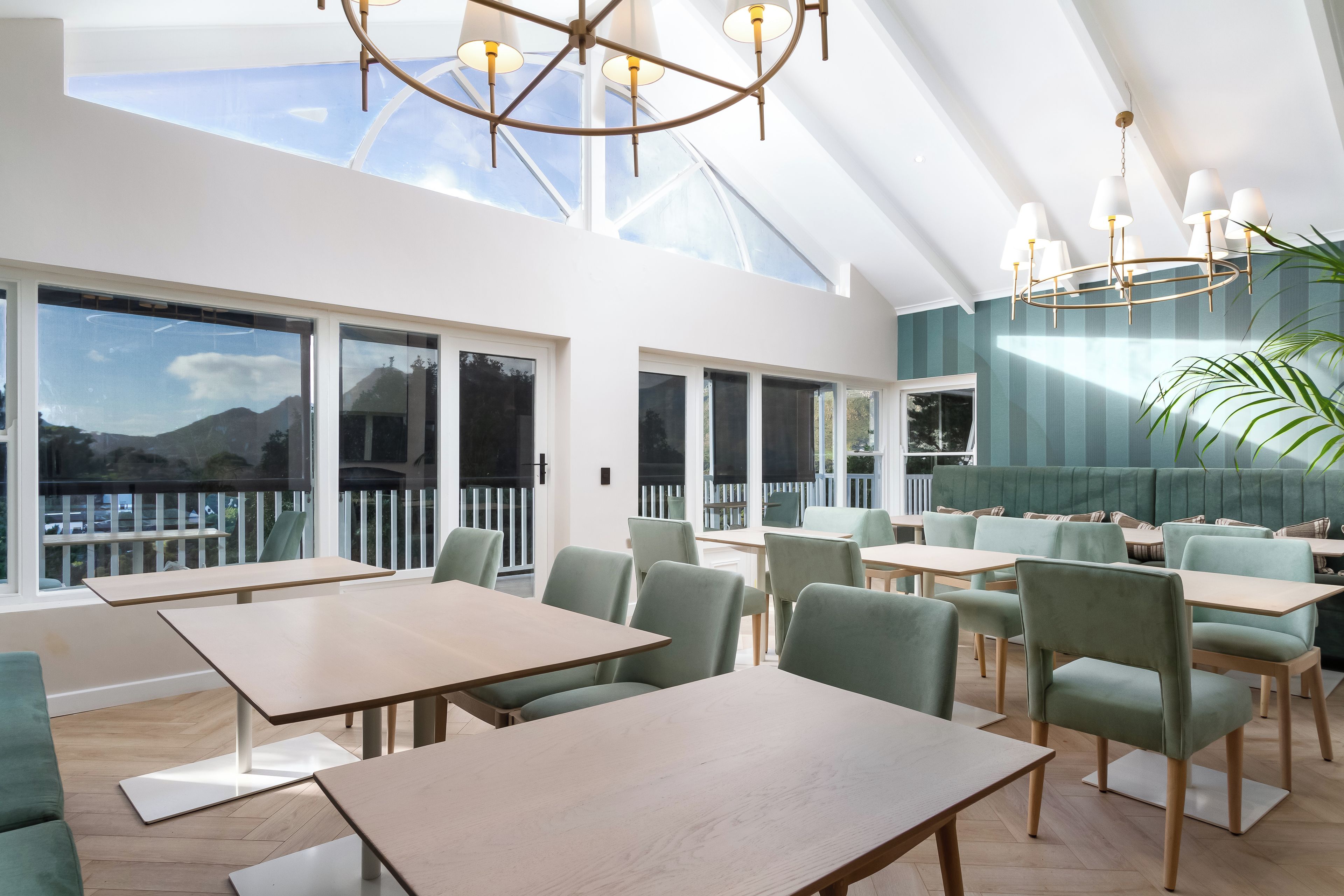 A modern dining area with tables and chairs, large windows, and a view of the outdoors.