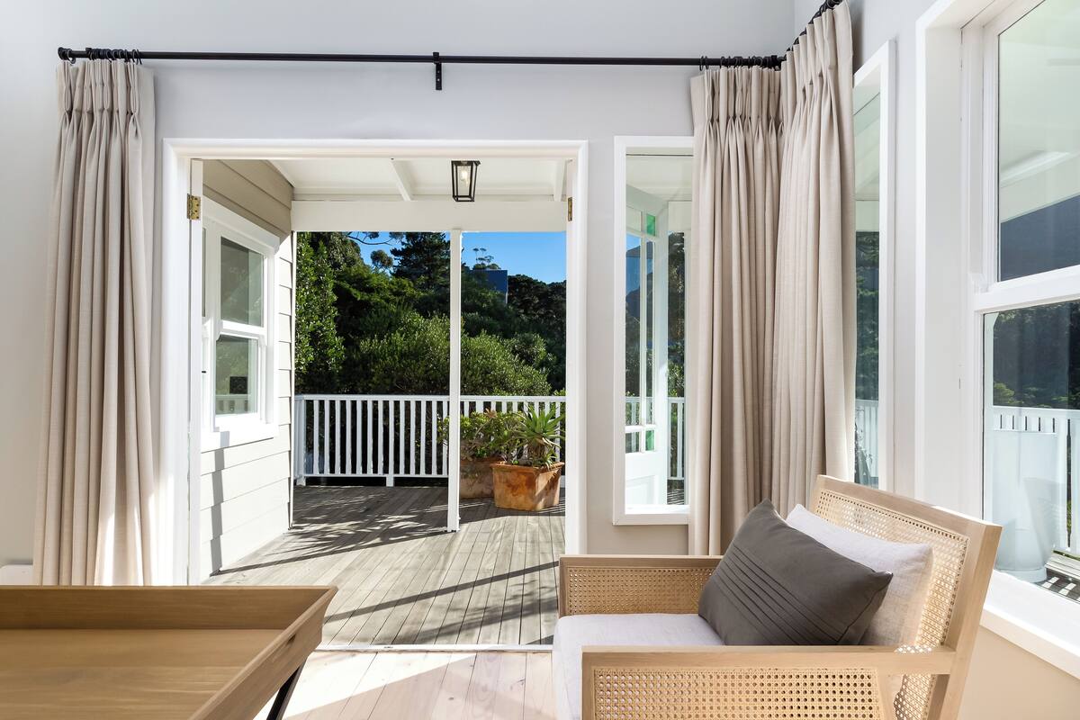 A balcony with a wooden floor, white railings, and a potted plant.