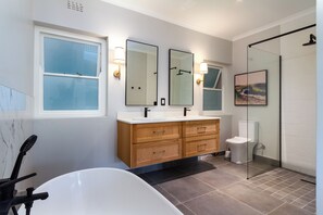 A modern bathroom with a bathtub, two sinks, a glass shower enclosure, and wooden cabinetry. - Bay Haven Collection, Hout Bay (Cape Town)