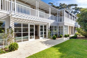 Une maison à deux étages dotée d’un balcon, de grandes fenêtres et d’une pelouse bien entretenue.