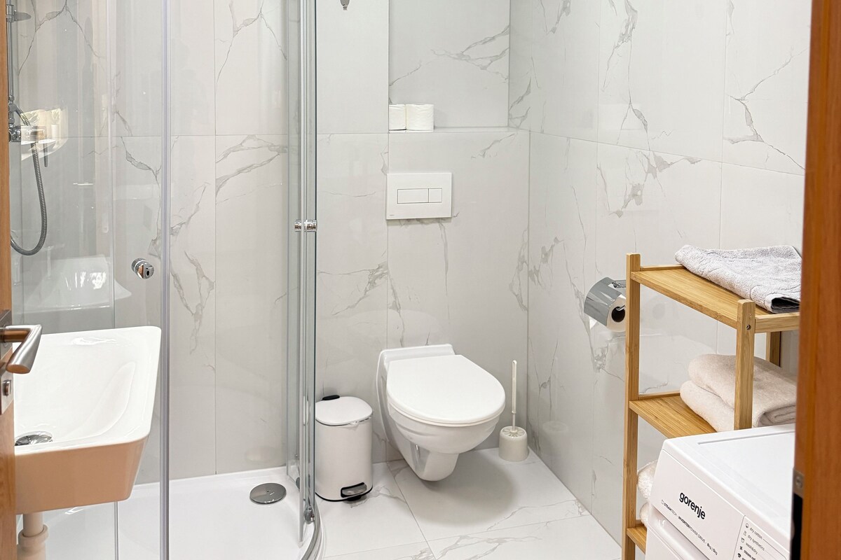 A modern bathroom with a glass-enclosed shower, a toilet, and a sink.