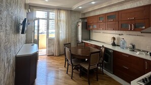Eine moderne Küche mit Holzausstattung, einem Esstisch mit Stühlen und einem eingebauten Backofen.