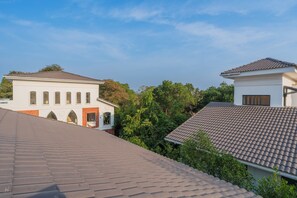 A residential area with two houses, one with a white facade and the other with a grey facade, both with tiled roofs. - Elivaas Laguna Aurelia - Goa (Vagator)