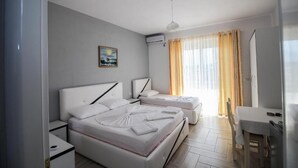 A modern hotel room with two beds, a desk, and a dining area. - Hotel Artur 2 (Sarandë)