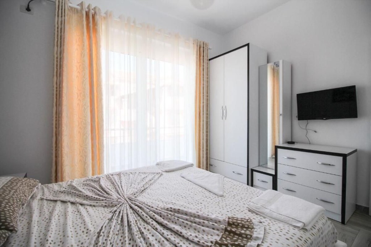 A bedroom with a bed, a wardrobe, a TV, and curtains.