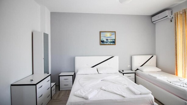 A modern hotel room with a bed, bedside tables, a dresser, and an air conditioning unit. - Hotel Artur 2 (Sarandë)