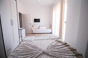 A bedroom with a bed, a TV on the wall, and a wardrobe. - Hotel Artur 2 (Sarandë)