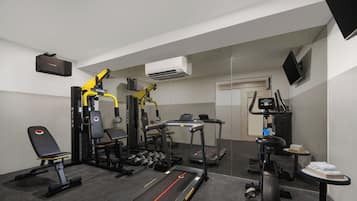 A gym with exercise equipment, a treadmill, and a bench.