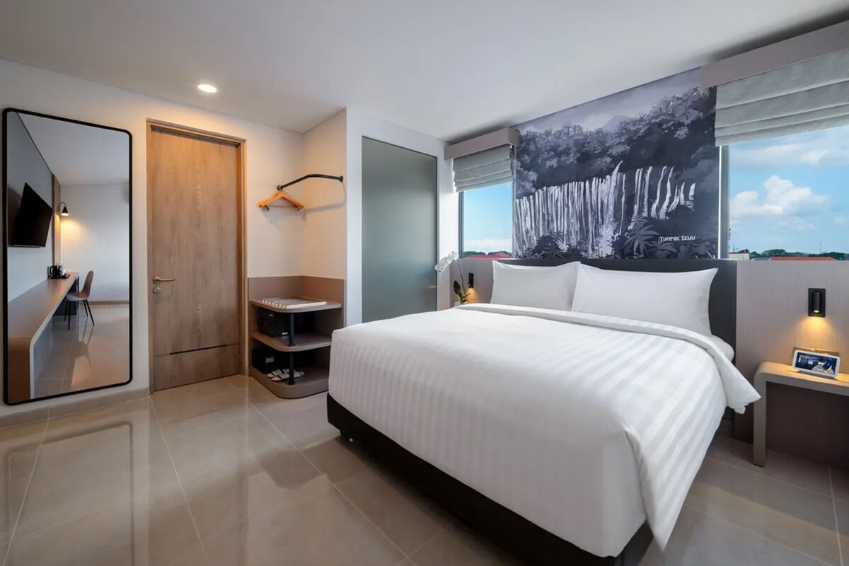 Ein modernes Hotelzimmer mit einem großen Bett, einem Schreibtisch und einer Sitzecke.