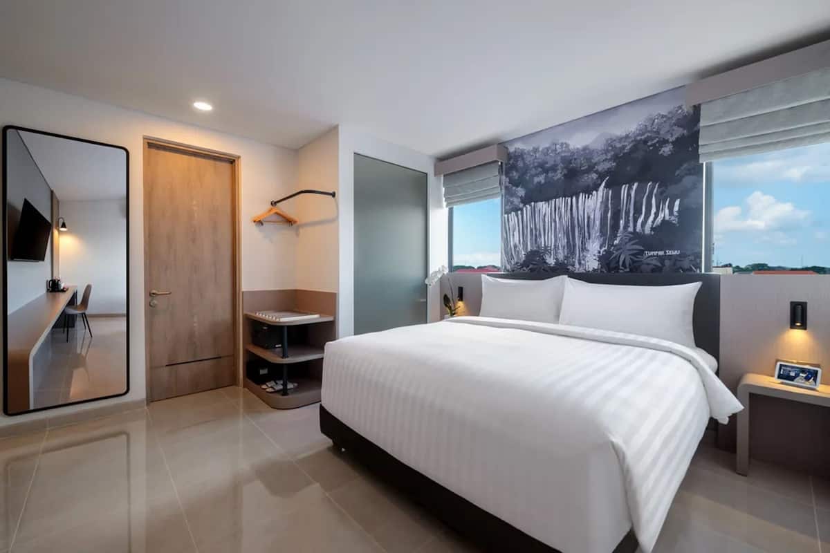Una habitación de hotel moderna con una cama grande, un escritorio y una zona de estar.