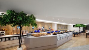 Un espace moderne dédié au petit-déjeuner, avec un comptoir central, des sièges et des plantes décoratives.