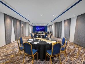 A conference room with a large round table, blue chairs, and a blue carpet. - Aston Inn Lumajang - East Java (Lumajang)