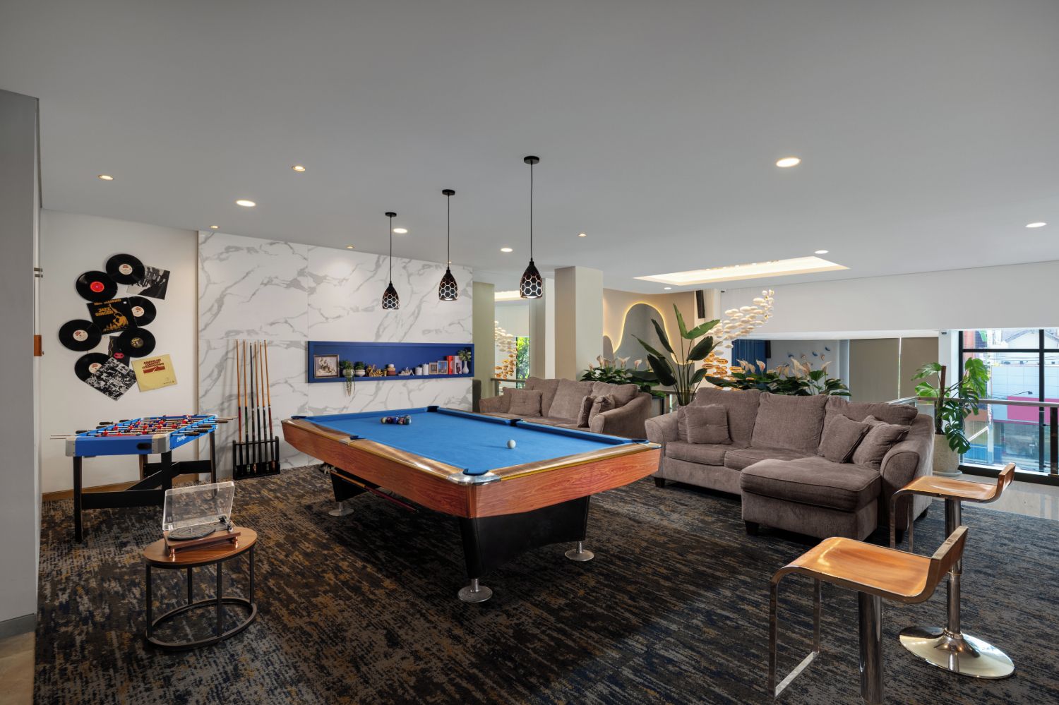 A pool table, sofas, and a foosball table in a modern lounge area.