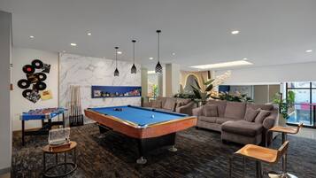 A pool table, sofas, and a foosball table in a modern lounge area.