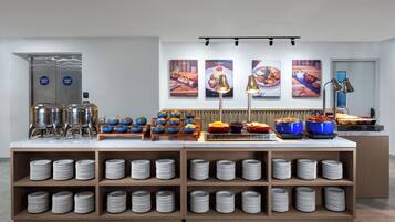 A buffet setup with multiple food stations, a coffee machine, and a self-service beverage dispenser.