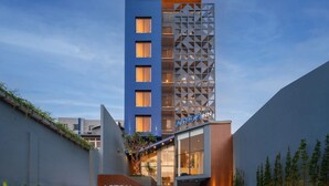 A modern hotel with a blue facade, a geometric patterned tower, and a visible sign for the Astor Inn.