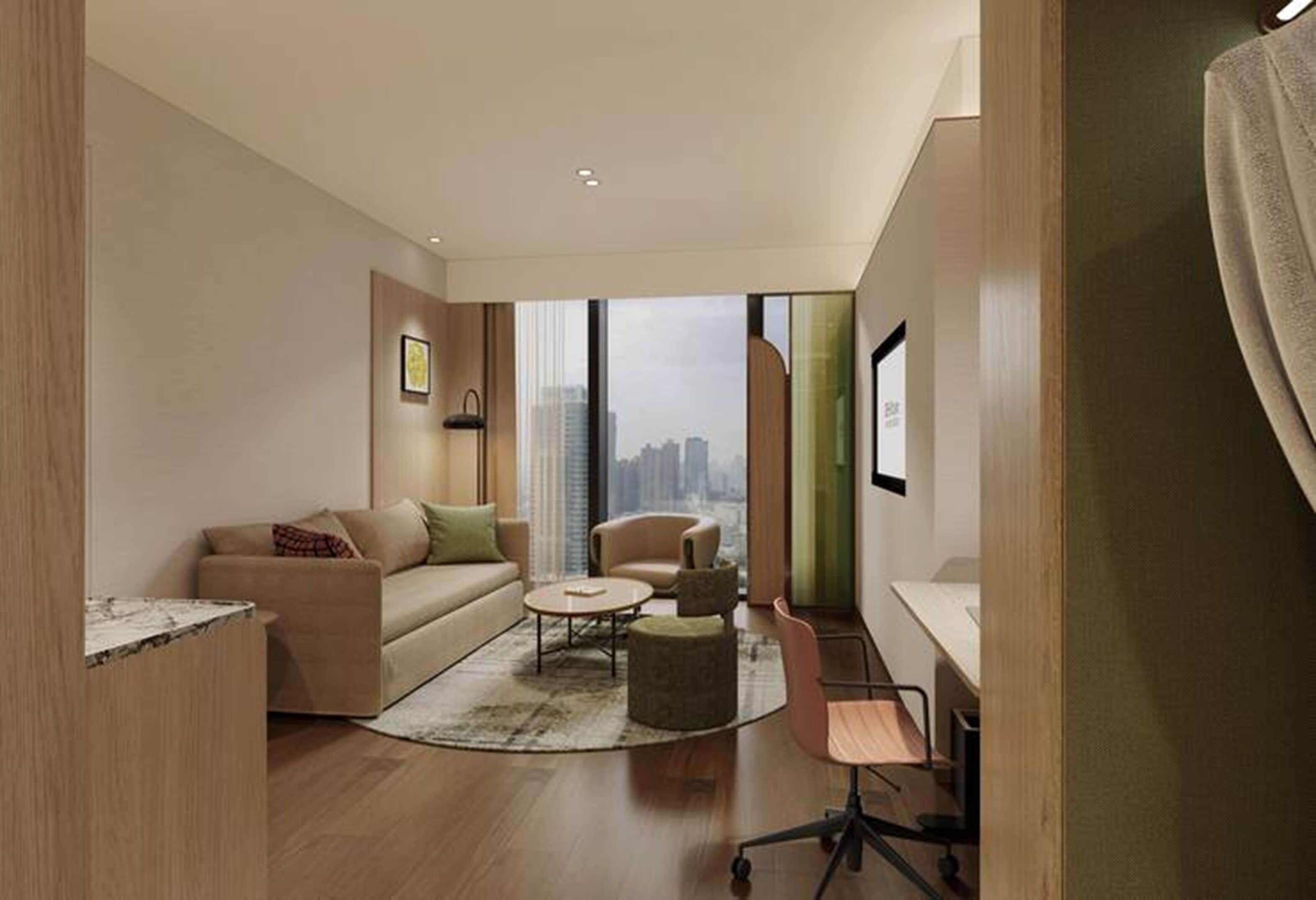 A modern living room with a sofa, armchair, coffee table, and a desk with a chair.