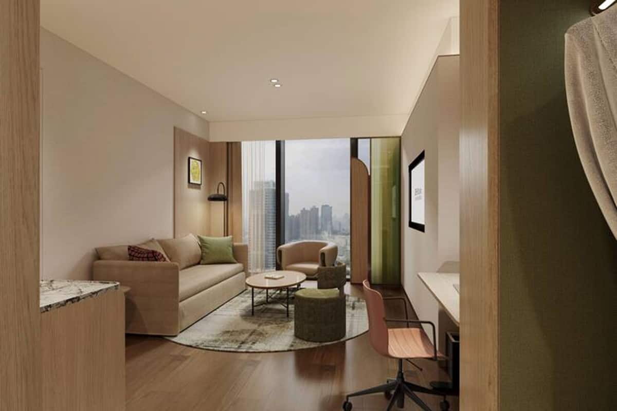 A modern living room with a sofa, armchair, coffee table, and a desk with a chair.