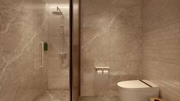 A modern bathroom with a glass shower enclosure, a toilet, and a small trash bin.