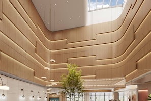 A modern interior with curved wooden paneling, recessed lighting, and a central tree. - Hilton Garden Inn Beijing Fengtai Xinxiang Buildin (Beijing)