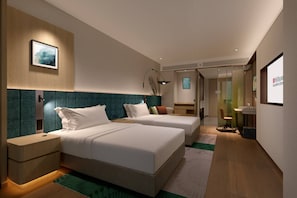 A modern hotel room with two beds, a desk, and a bathroom.