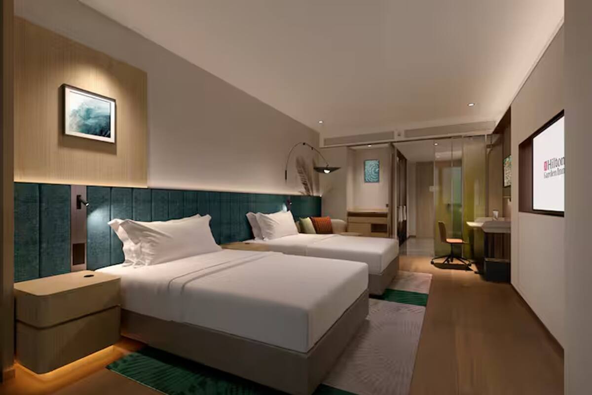 Une chambre d’hôtel moderne avec deux lits, un bureau et une chaise.