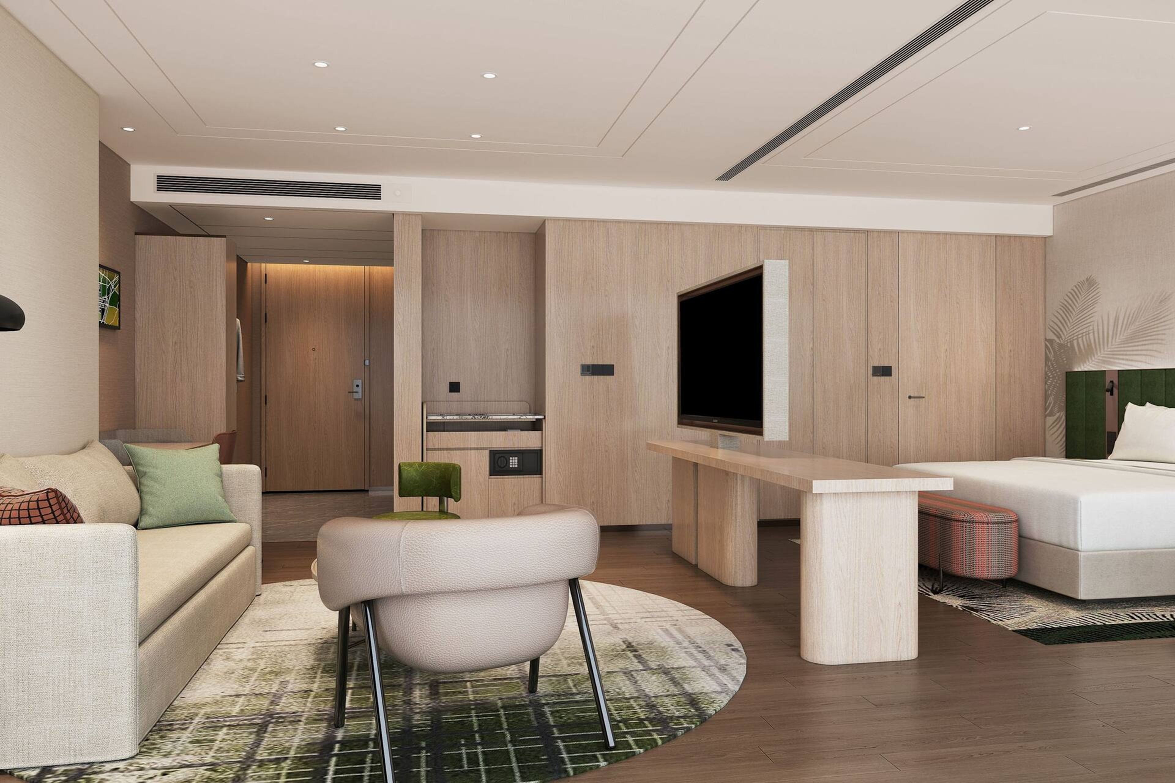Une chambre d’hôtel moderne équipée d’un canapé, d’un fauteuil, d’une télévision, d’un bureau et d’un lit.