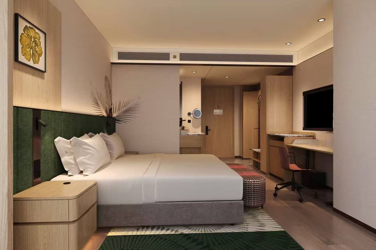 Une chambre d’hôtel moderne équipée d’un lit, d’une table de chevet, d’un bureau, d’une chaise et d’un téléviseur.
