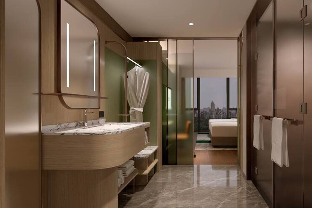 Une salle de bain moderne avec un meuble-lavabo en marbre, une douche à parois de verre et une vue sur le paysage urbain, visible à travers une porte coulissante.
