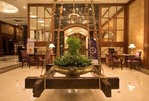 A lobby with a central swing chair, a chandelier, and a large potted plant. - Ira By Orchid Mumbai - T2 International Airport (Mumbai)