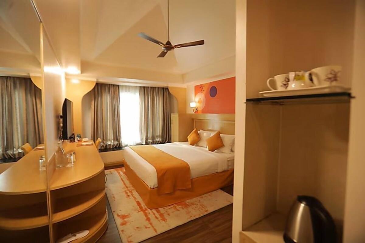A hotel room with a bed, a desk, a ceiling fan, and a coffee table.