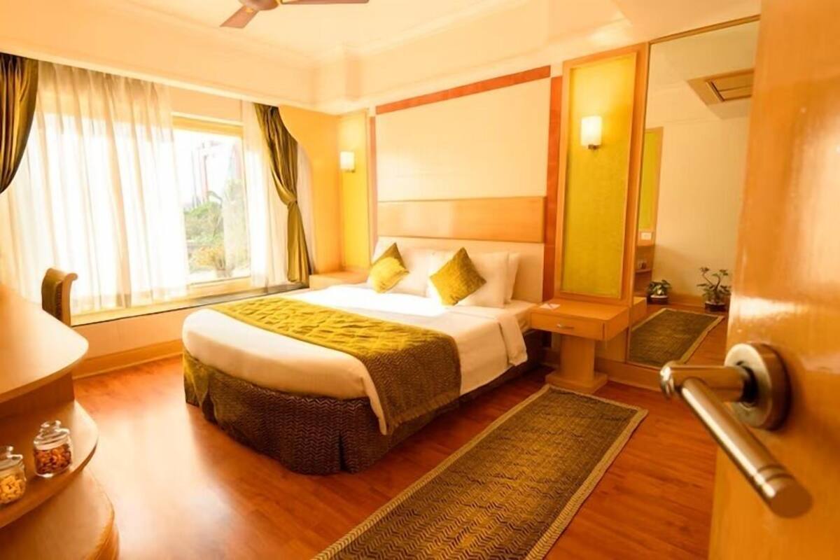 Ein Hotelzimmer mit Bett, Nachttisch und einem fenster mit Vorhängen.