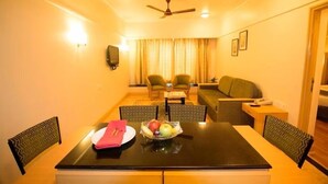 A hotel room with a dining table, chairs, a sofa, and a ceiling fan. - Ira By Orchid Mumbai - T2 International Airport (Mumbai)